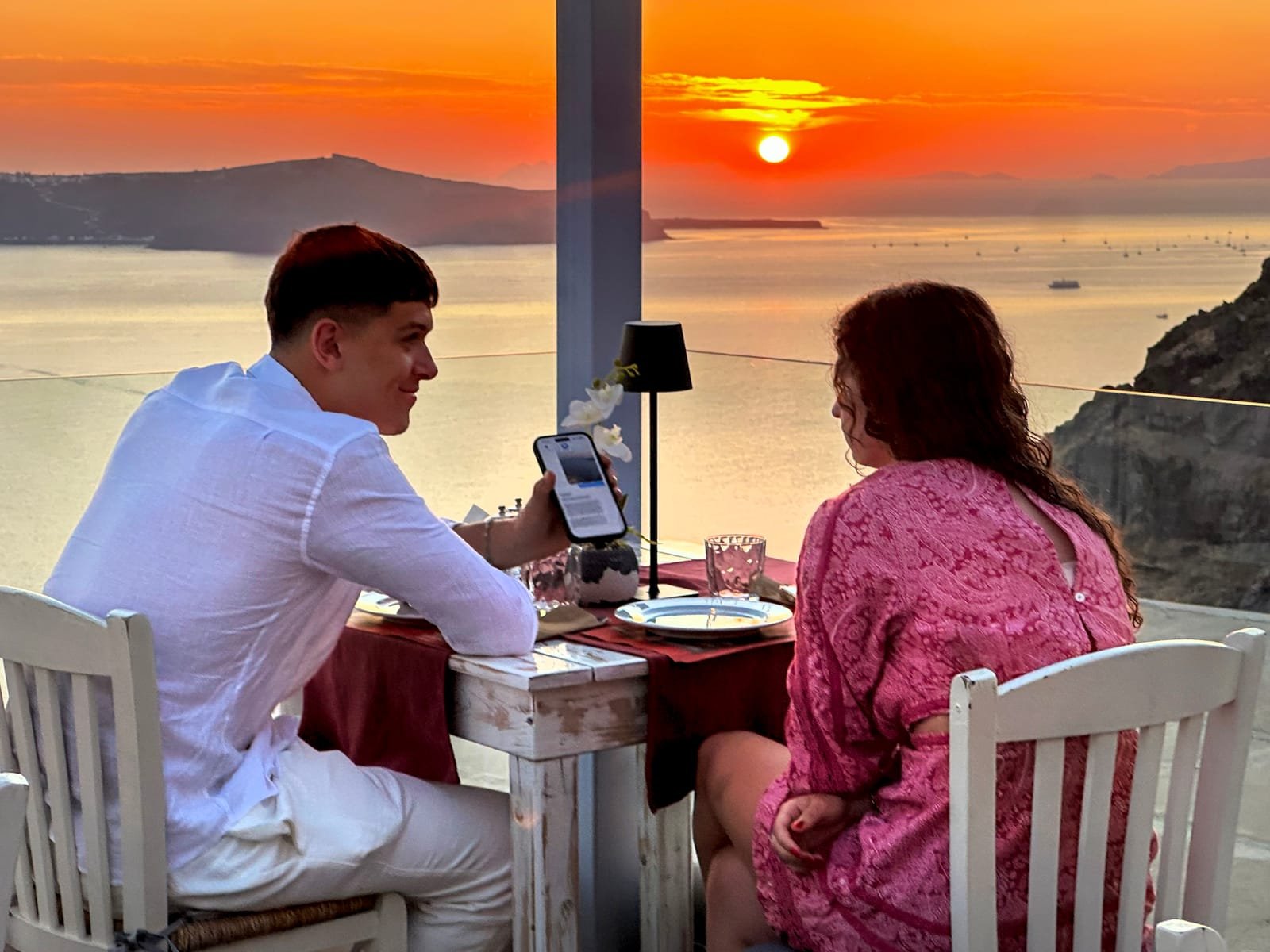 Lithos Restaurant, Fira, Santorini — couple dining at a caldera-view table at sunset