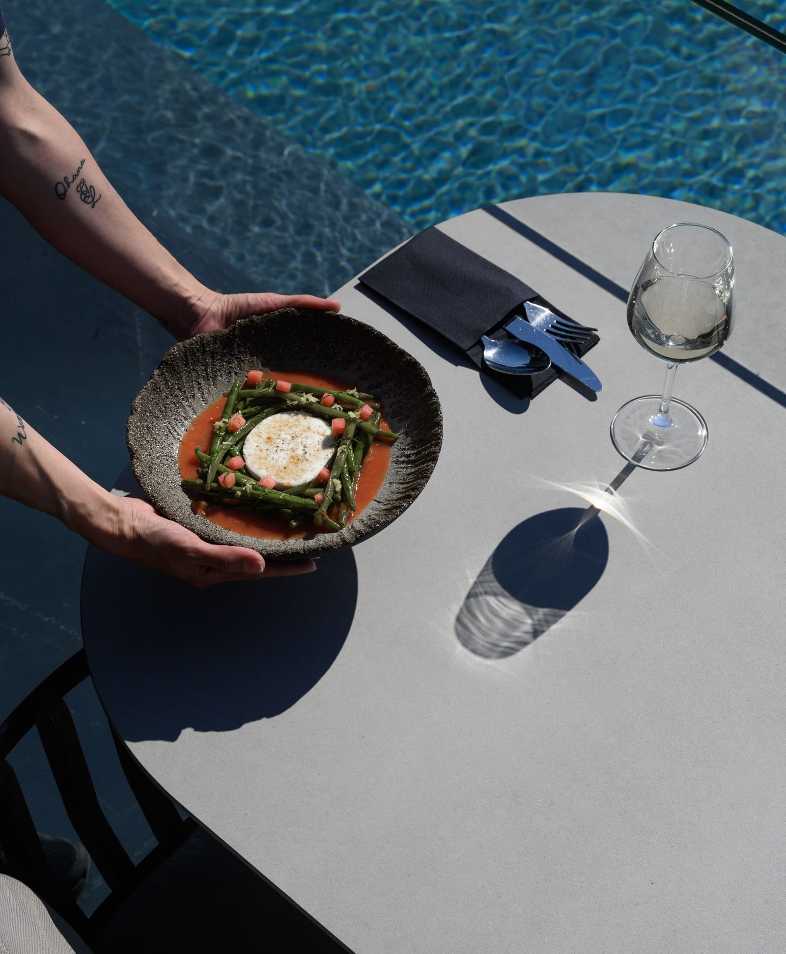 Mavro Restaurant, Imerovigli, Santorini — plated dish and a glass of white wine by the pool