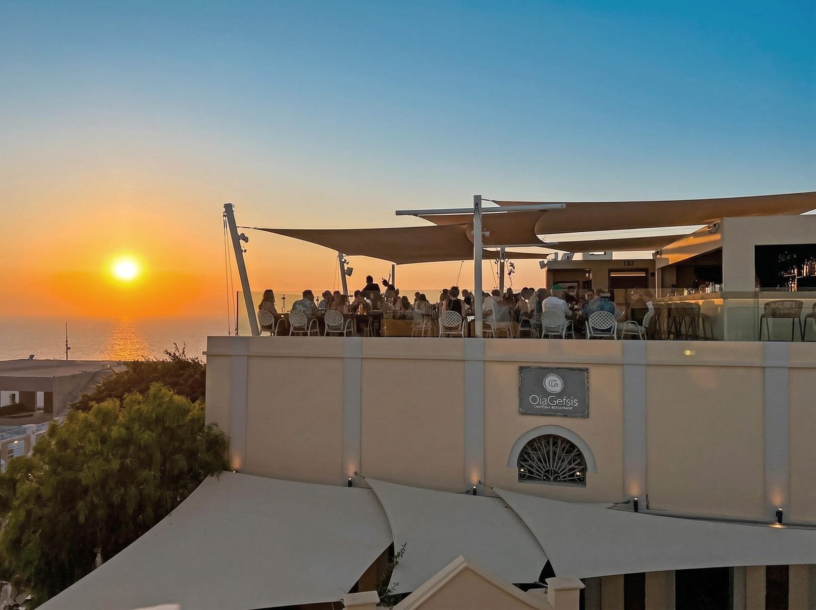 Oia Gefsis, Oia, Santorini — rooftop terrace and restaurant facade at sunset over the sea
