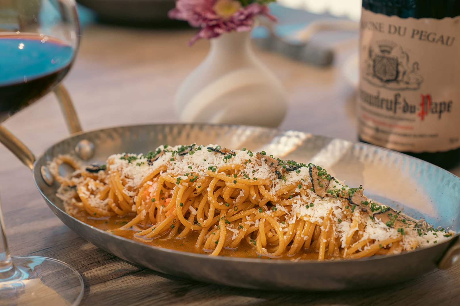 Oia Gefsis, Oia, Santorini — truffle and parmesan spaghetti in a steel pan beside a glass of red wine