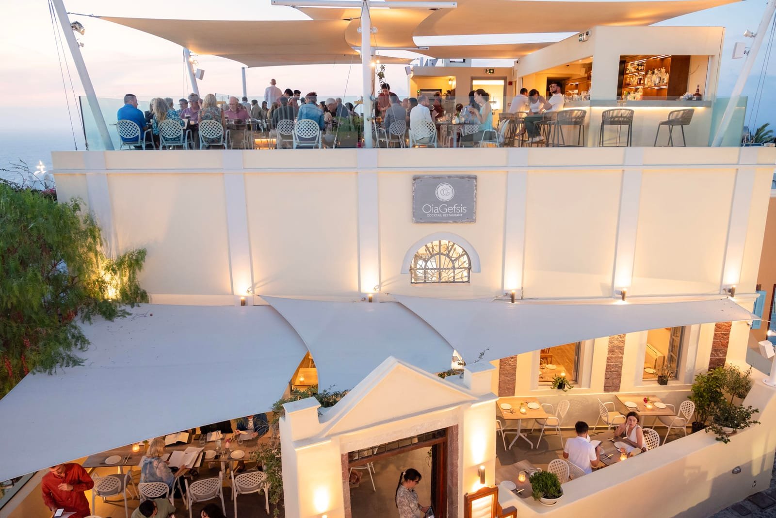Oia Gefsis, Oia, Santorini — restaurant facade and rooftop terrace lit up at dusk