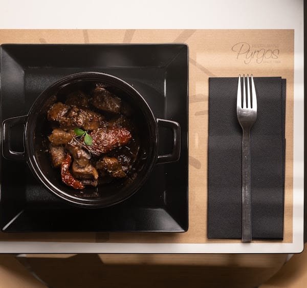 Pyrgos Restaurant, Pyrgos, Santorini — slow-cooked beef in a black pot on a wooden tray
