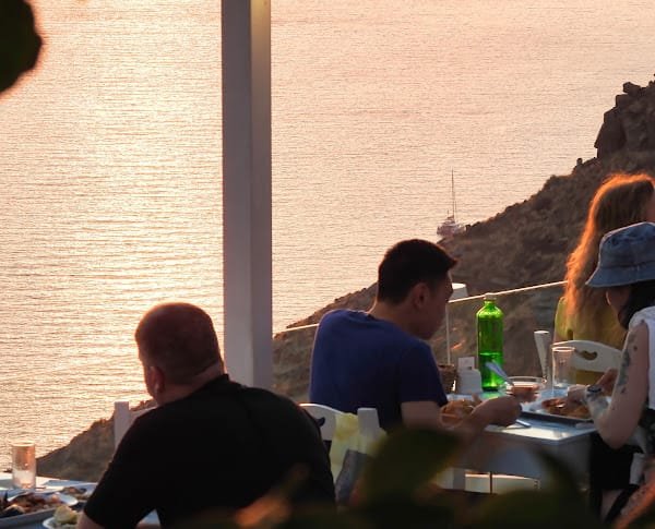 Volcano Blue Seafood Restaurant, Fira, Santorini — diners on the caldera terrace at sunset